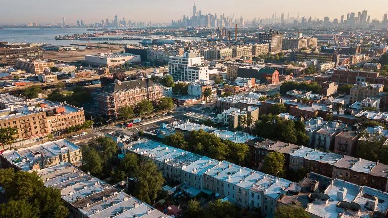 An aerial view of homes in the Sunset Park neighborhood, New York City, the Manhattan skyline visible in the distance.