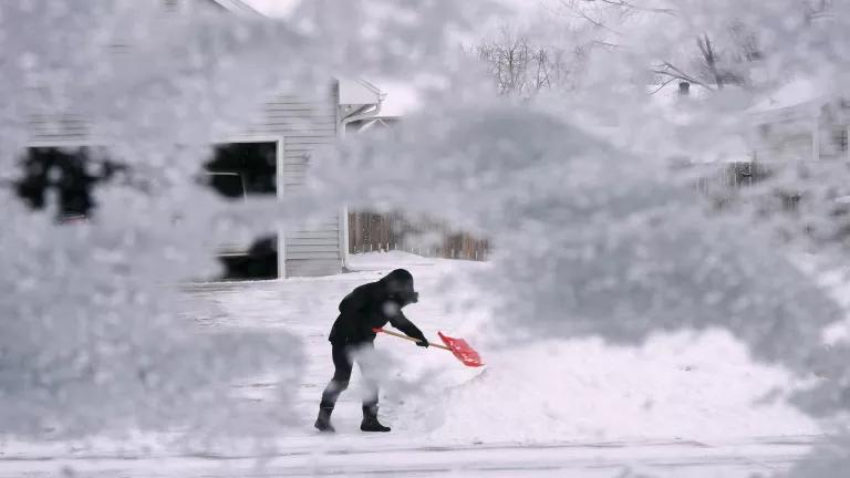A person shoveling snow from their driveway during a winter storm