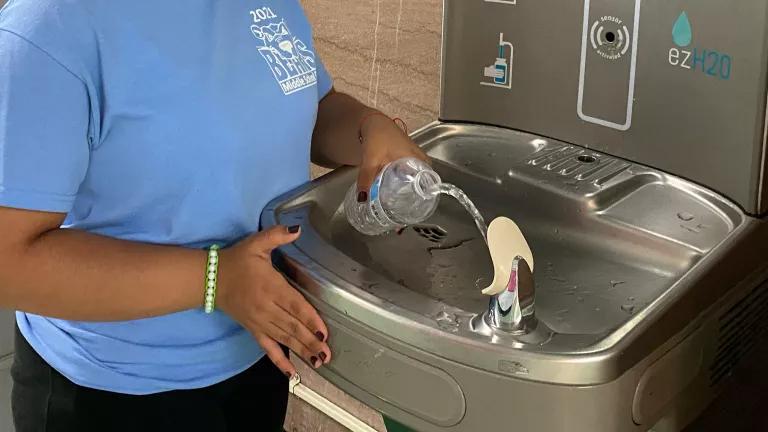 A student filling her water bottle from a filtered drinking fountain at a school