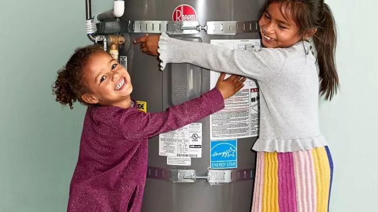 Two children hugging a heat pump water heater.