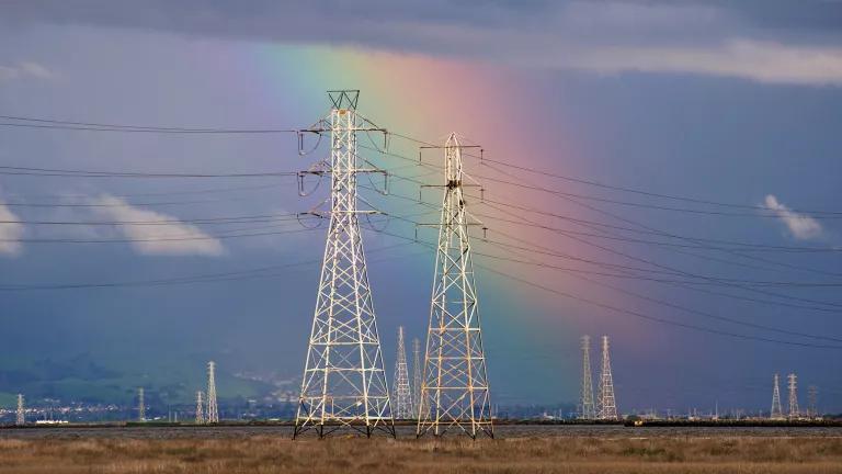 A rainbow behind pylons and power lines in a California wetland