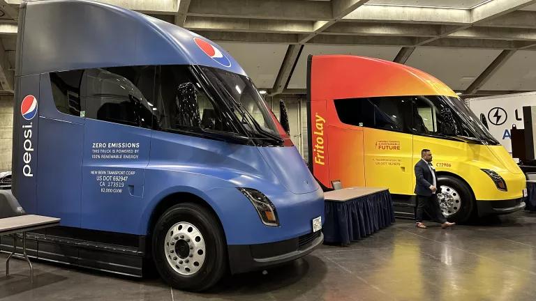 Tesla Semi Trucks parked within an auditorium at a vehicle showcase. 