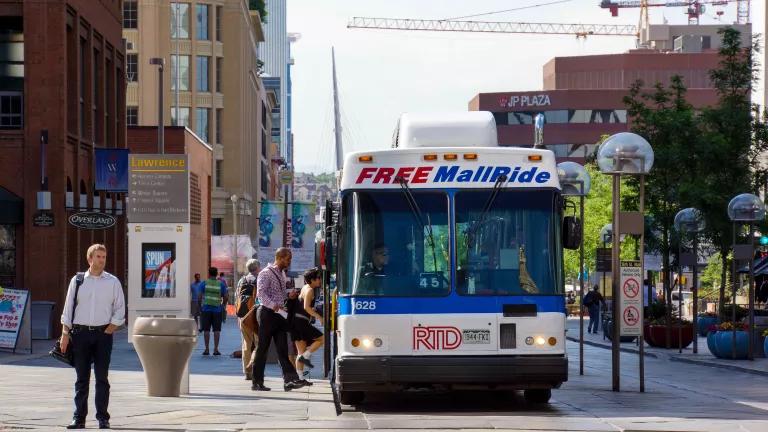 Bus riders board the Free MallRide bus in Denver, Colorado as a person waits to cross the street