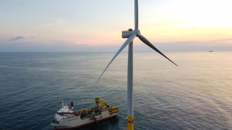An aerial view of an installation vessel beside a wind turbine at Coastal Virginia Offshore Wind, at sunset