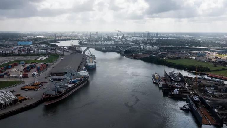 A narrow waterway with ports and industrial facilities lining the banks on both sides