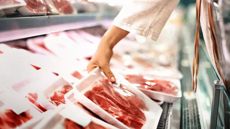 A customer picking up a package of beef sirloin steaks in a supermarket.
