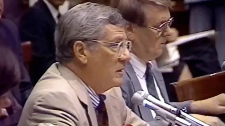 A man sits and speaks into a microphone