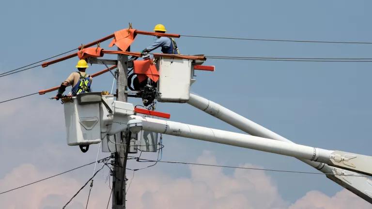 Utility workers in a cherry picker examining power lines