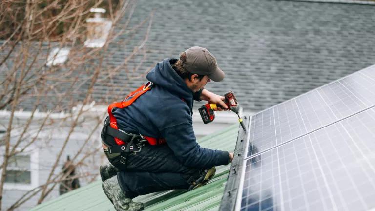 A Renovus Solar worker installing a rooftop solar panel on a home in upstate New York.