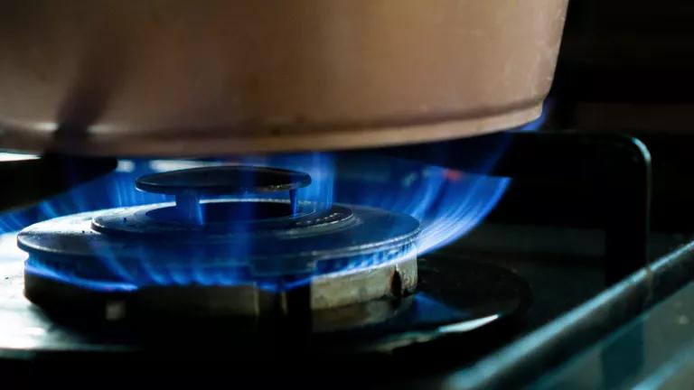 A gas stove turned on with a blue burner flame 