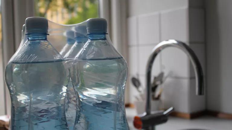 A six pack of bottled water on a kitchen counter.