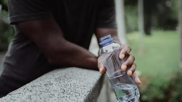 A man drinking out of a plastic water bottle.