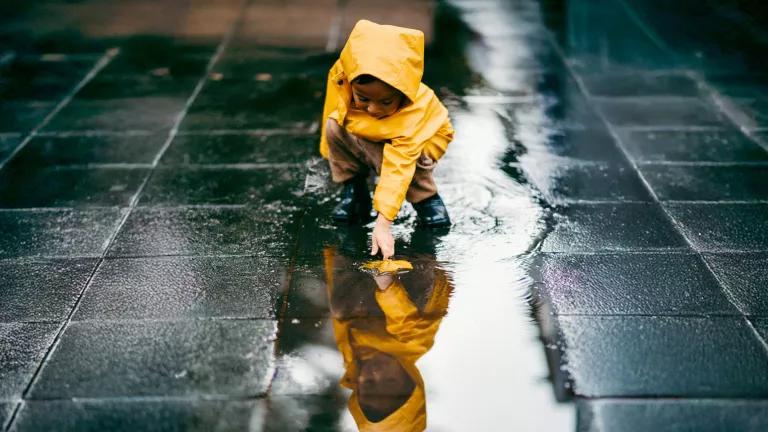 A child wearing a waterproof jacket and boots on a rainy fall day.
