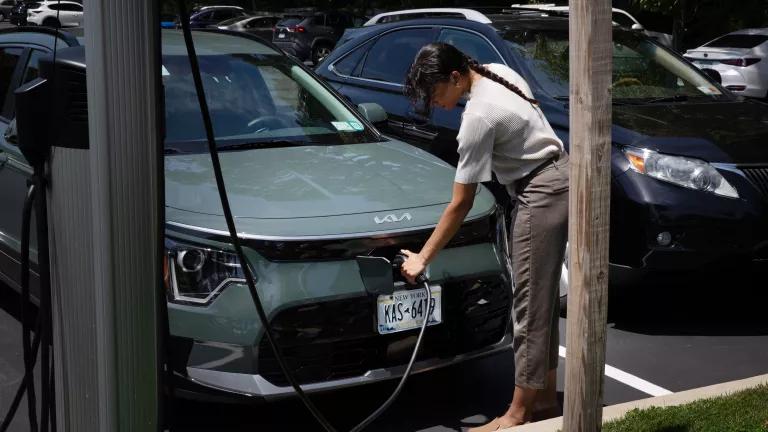 A woman plugging her electric car into a ChargePoint EV charging station in the Half Hollow Hills Community Library parking lot, Dix Hills, New York, on June 20, 2024.