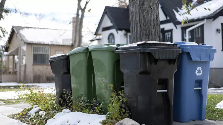 Garbage, recycling, and composting/organics bins awaiting pickup in a suburban neighborhood in Canada.