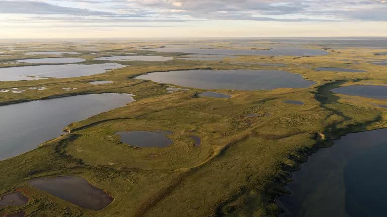 A wide angle aerial view of the site of ConocoPhillips' completed Tinnik-3 winter exploration well amid waterways in the Western Arctic Reserve on Alaska's North Slope. Scars left on the tundra by an ice road and pad are visible.