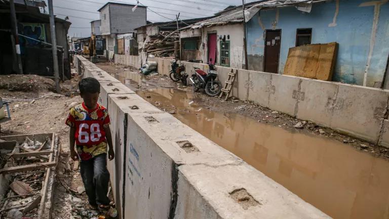 A young boy walking by the tidal flood mitigation embankment project under construction in Muara Angke, Jakarta, Indonesia, on January 6, 2026.The Jakarta Provincial Government accelerated the construction of the 1,390-meter embankment to mitigate tidal flooding caused by land subsidence in the area. 