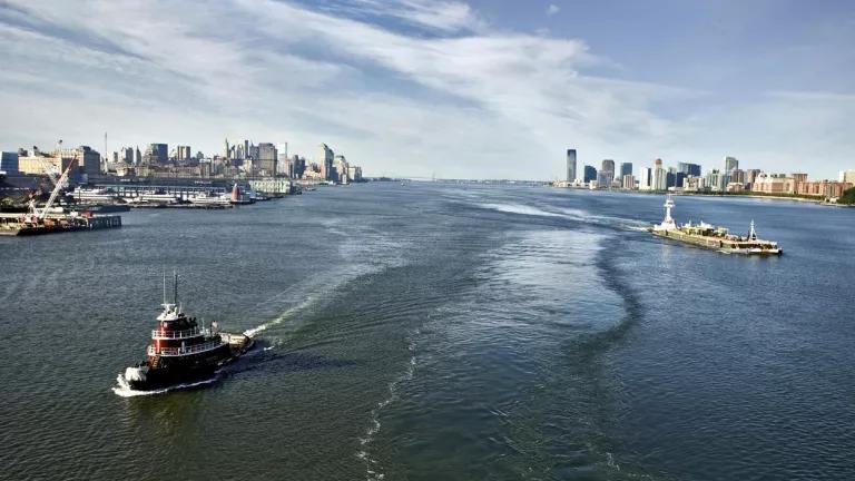 An aerial view of a tugboat and a barge sailing on the Hudson River