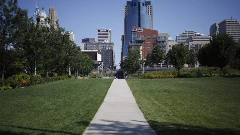 Cincinnati buildings, blue sky, green grass with paved sidewalk into the horizon.