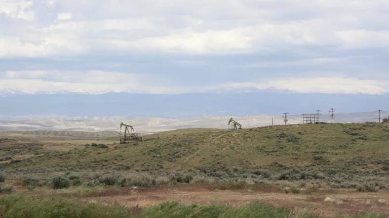 A picture containing grass, outdoor, sky, field, and pump jacks. 