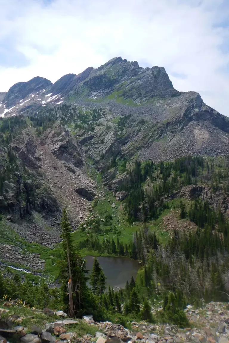 A small lake in a valley at the foot of a rocky mountain face