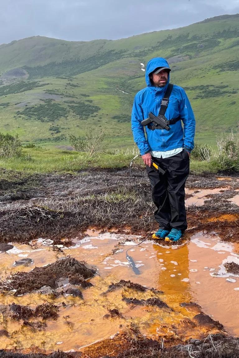 Patrick Sullivan, part of a team of scientists testing water quality in Kobuk Valley National Park's Salmon River, standing by an acid seep on July 15, 2023. 

Sullivan is part of a team of scientists who tested water quality in the Salmon River and its tributaries, where permafrost thaw has caused acid rock drainage. The process is releasing metals that have turned the waters a rusty-looking and opaque.