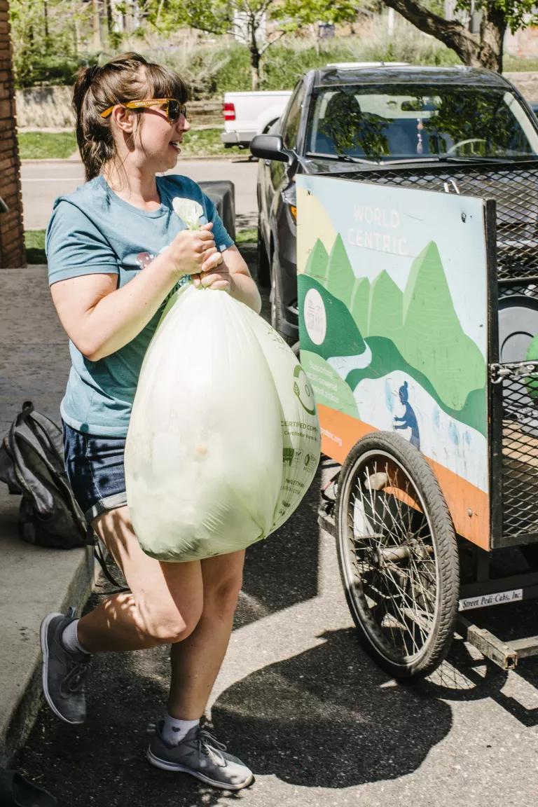 A woman carries a bag toward a small trailer
