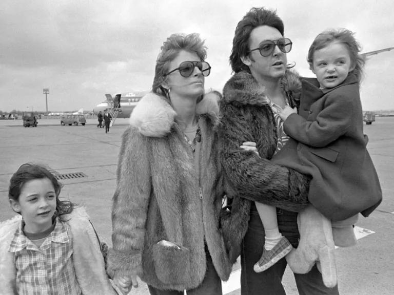 A black and white image of Linda and Paul McCartney on an airfield with two young children