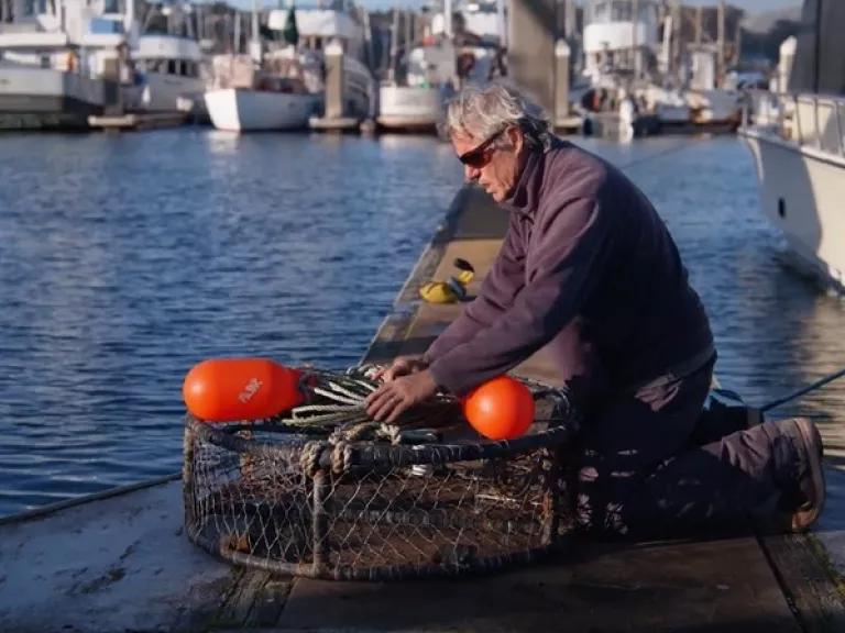 A man sitting by the water preparing his fishing gear technology for dockside testing