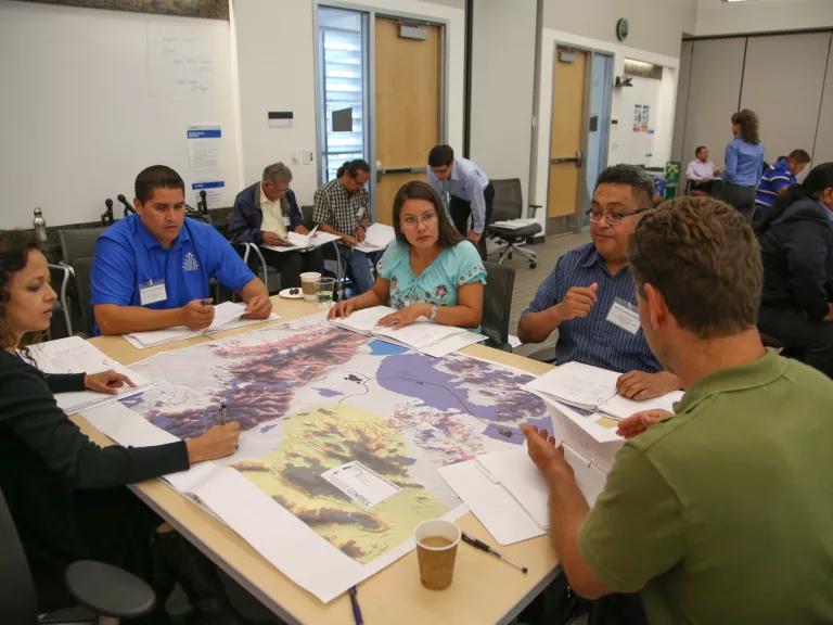 Five people sitting around a table looking at a map