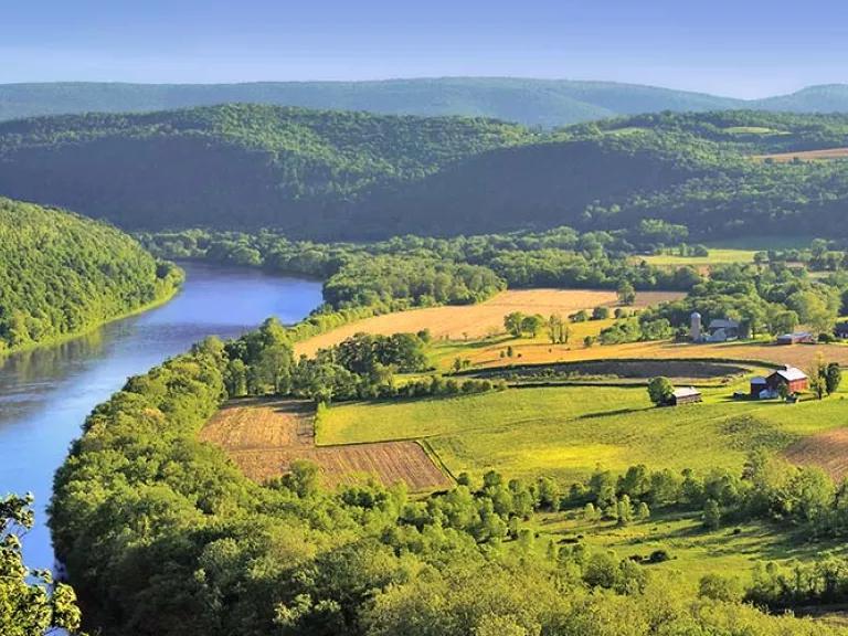 Tree-lined river landscape with farm fields nearby