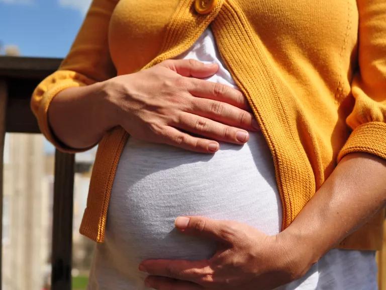 A pregnant woman gently holds her belly