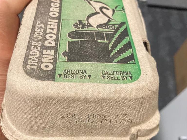 The end of a carton of eggs with a stamped date below the printed labels "ARIZONA BEST BY" and "CALIFORNIA SELL BY"
