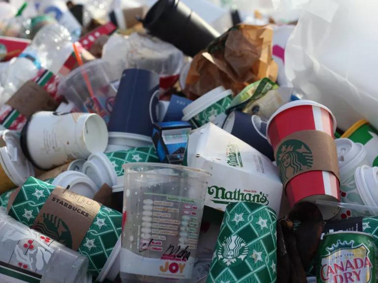 A pile of discarded single-use plastic and paper food packaging and cups.