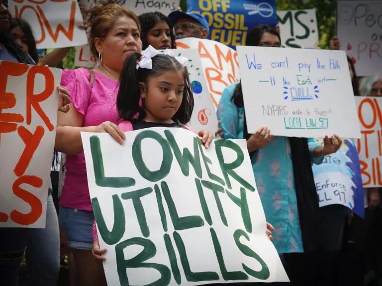 A young girl holding a sign that reads 'Lower Utility Bills' at the Rally to Enforce NYC's Climate Law outside City Hall in Manhattan, New York City, on July 13, 2023.

The rally was held to demand Mayor Eric Adams fully implement Local Law 97, New York City’s Green New Deal for Buildings.