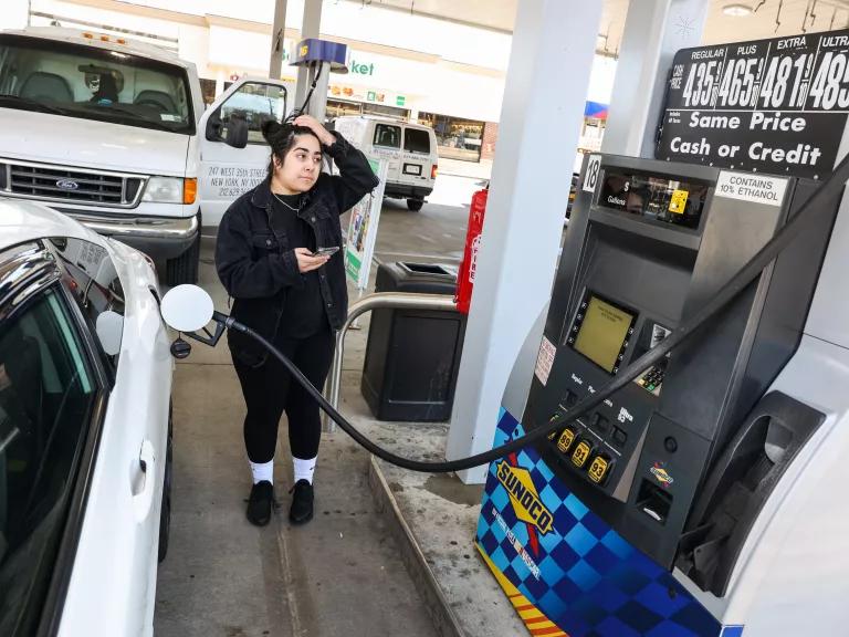 A person at a gas station holding a gas pump