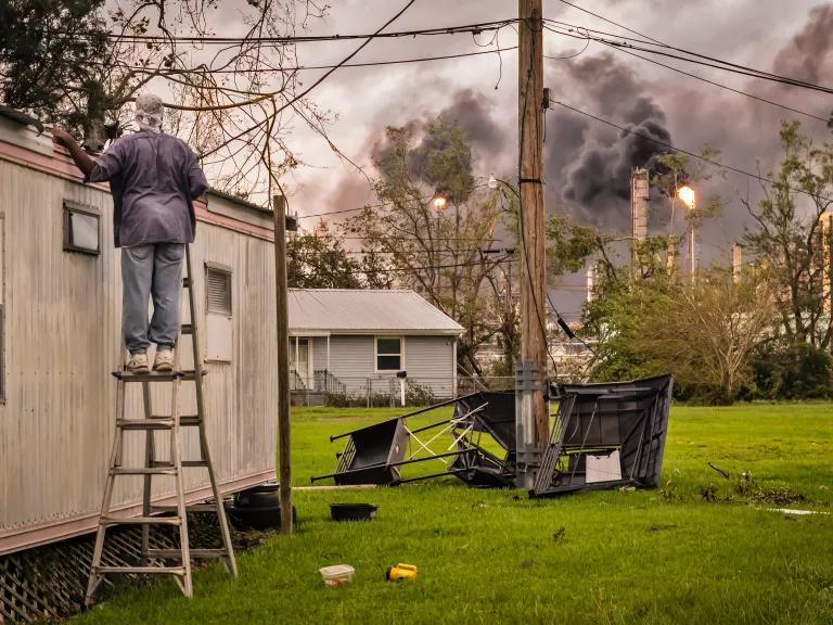 A local resident looks toward the burning gas flare of a nearby oil refinery as he repairs damage on a property in an area known as 'Cancer Alley’ in Baton Rouge, Louisiana, following Hurricane Ida in September 2021.
