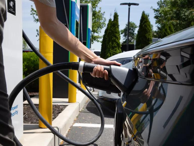 A woman plugging her electric car into an EVolve NY charging station in a shopping center parking lot in Commack, Long Island, New York, on June 20, 2024.