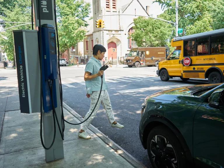 A woman charging her electric car at a public charging station in Brooklyn, New York City.