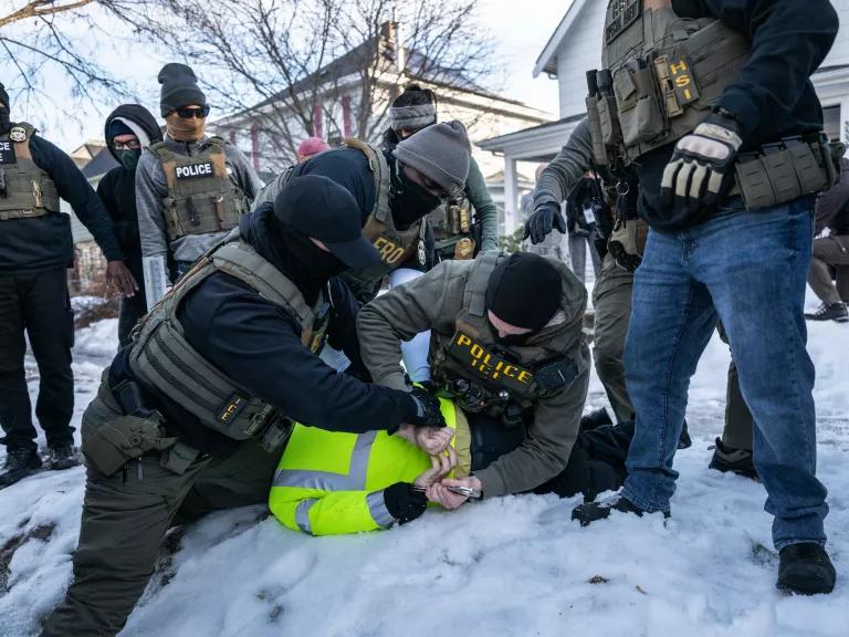 Federal law enforcement agents detain a demonstrator during a raid in south Minneapolis, Minnesota, on January 13, 2026. Minnesota officials are suing over the unprecedented surge of US immigration authorities in the state, taking the Trump administration to court days after a federal agent shot and killed a Minneapolis woman.