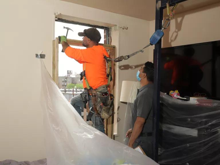 Francis Rodriguez, Director of weatherization at the nonprofit Association for Energy Affordability (AEA), assists an AEA worker installing a new energy efficient window at an apartment in the South Bronx, New York City.