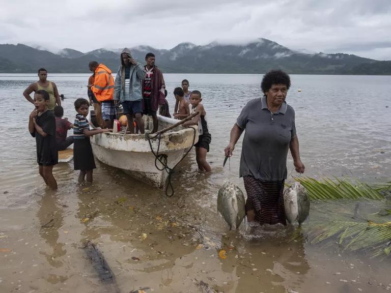 Fishermen sell the day's catch to community members straight from their boat in Muani, Kadavu, Fiji, on March 29, 2025.

Muani, a coastal community that relies heavily on fishing, faces risks of storm surge and sea level rise due to climate change. Community residents have constructed a drainage network to mitigate surface run-off. They also have a stone seawall which sits at the same height as the village ground during high tide, which does not protect them from flooding and large parts of the village are 