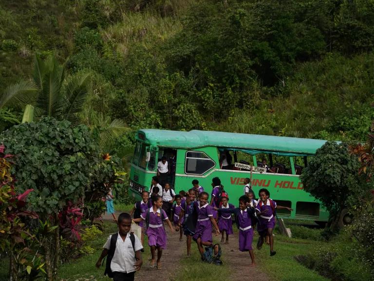 Children get off a school bus as they return home for the day to the new relocated site of Vunidogoloa Village, Vanua Levu, Fiji, on July 20, 2022. 

In 2014 Fiji, an archipelago of hundreds of islands, became the first Pacific island nation to relocate a community because of rising sea levels.