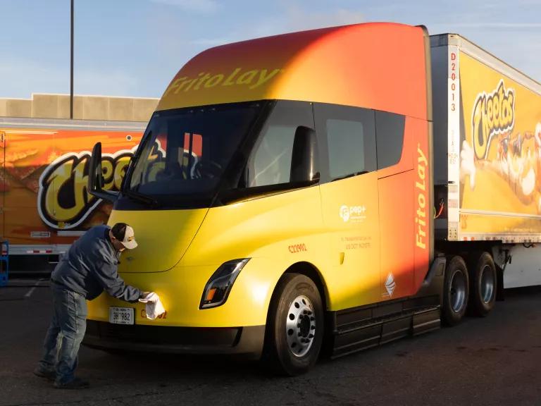 A worker cleans a Tesla semi-trailer electric truck parked outside the Frito-Lay manufacturing facility in Modesto, California, US, on January 18, 2023. PepsiCos Frito-Lay is replacing its diesel-powered freight equipment with zero-emission trucks,  solar panels and energy-storage systems at it's Modesto plant.