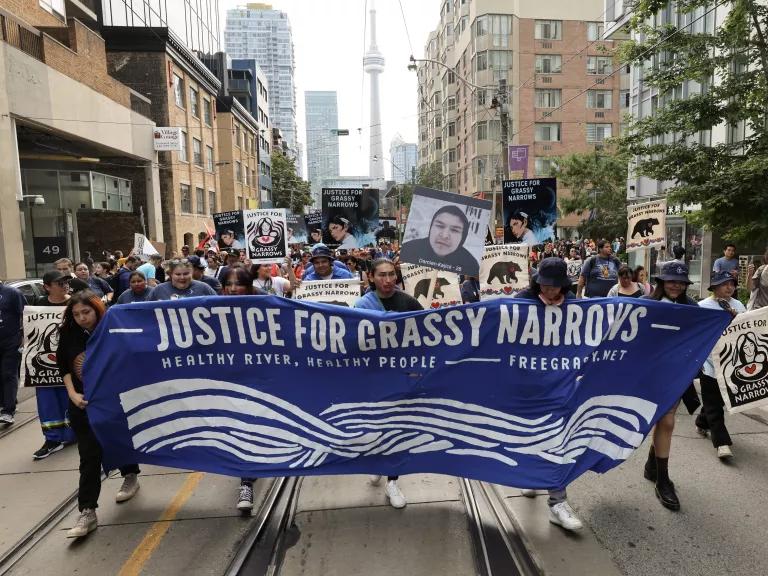 Thousands marched through the streets of Toronto on Wednesday to protest the situation in the Grassy Narrows indigenous community. They marched from Grange Park to Queen's Park where they unfurled a 1,600 square foot banner calling for justice. Grassy Narrows is demanding fair compensation, an end to industrial threats to Grassy Narrows lands, water, and people, and support to restore their way of life and wellbeing.