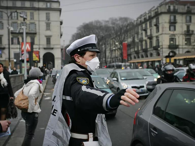 An officer wearing a face mask directs traffic on a city street