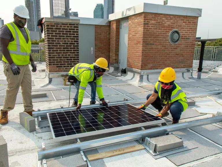 Workers install¬¬ rooftop solar panels on a building in NYCHA’s Queensbridge Houses in Long Island City, Queens, New York City.