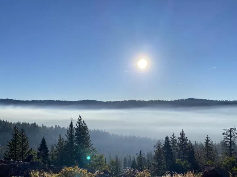 The sun shines over a mist-covered valley