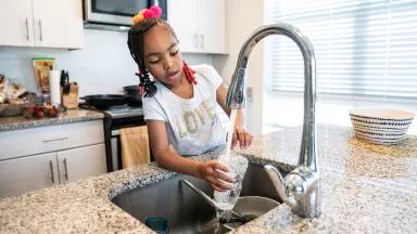 Liyah Watkins, 5, filling a glass of water in the kitchen sink at her home in Washington, DC.