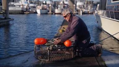 A man sitting by the water preparing his fishing gear technology for dockside testing